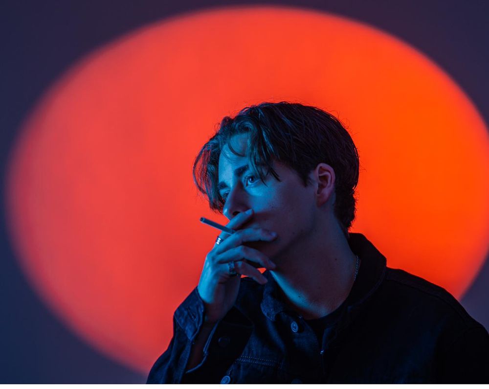 Portrait of a young man lit by a red circular spotlight