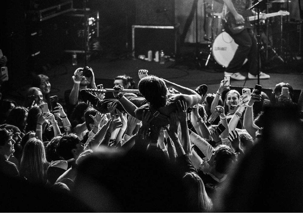 Singer crowd-surfing over a packed floor